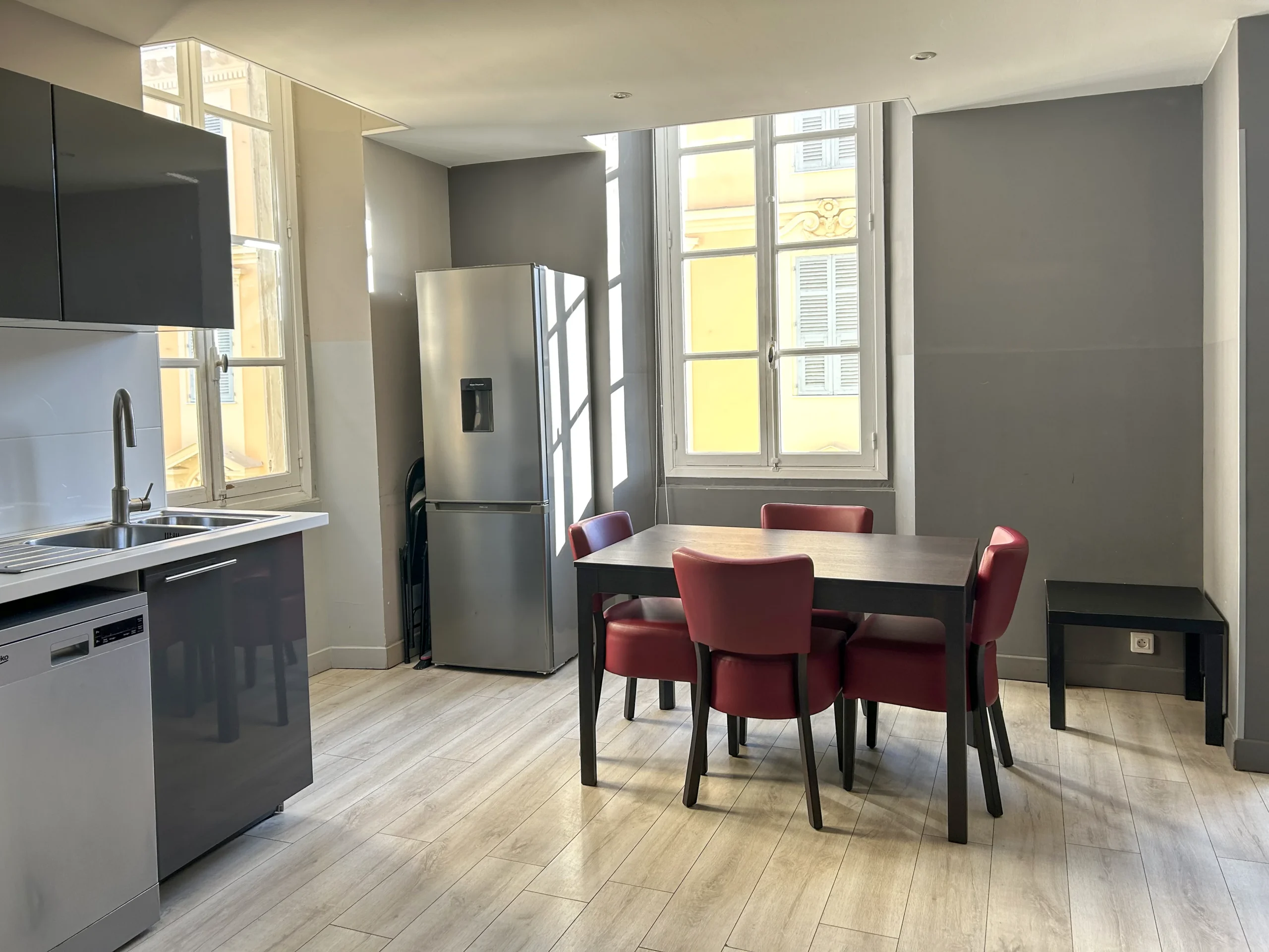 Coin repas avec réfrigérateur et vue sur les façades niçoises – Appartement Plain-Pied, Carré d'Or Nice