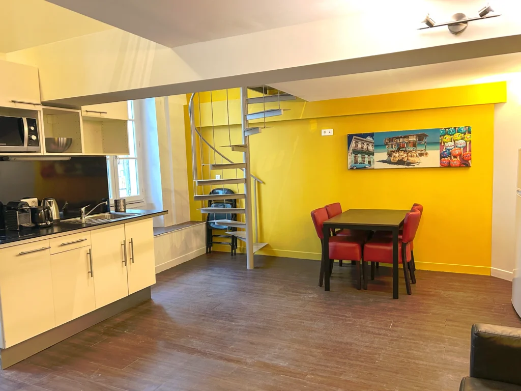 Cuisine ouverte sur le coin repas avec table et chaises rouges – Grand Loft 3 Espaces, Carré d'Or Nice